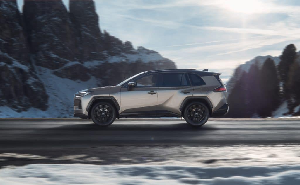 Silbernes SUV fährt auf verschneiter Straße in winterlicher Berglandschaft.