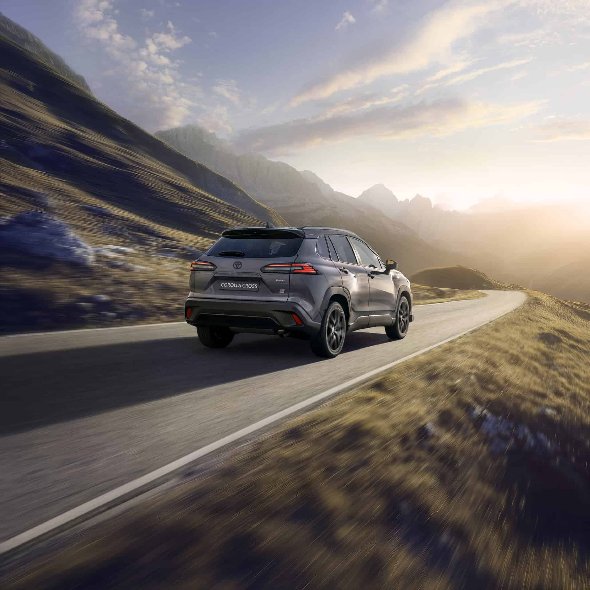 Toyota Corolla Cross auf einer kurvigen Bergstraße bei Sonnenuntergang.