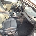 Fahrzeug-Innenraum mit Ledersitzen und digitalem Armaturenbrett.